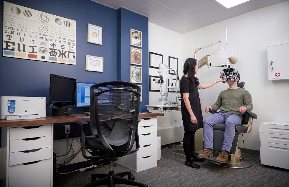 An eye examination in progress at the clinic, the phoropter positioned in front of the patient